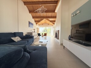 Una sala de estar moderna con techo de madera, un televisor grande y un sofá.