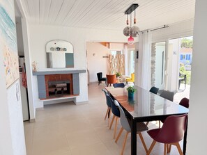 Un comedor moderno con una mesa de vidrio, sillas de madera y una chimenea.