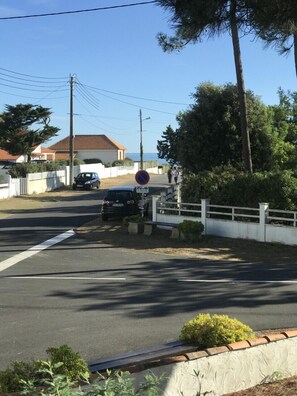 Una calle residencial con un cartel de no estacionamiento, un coche aparcado y casas con tejados de tejas rojas.
