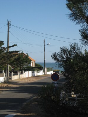 Una carretera costera con un cartel de prohibido estacionar, un edificio blanco con techo rojo, y vistas al mar.