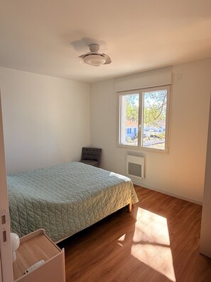A bedroom with a bed, a window, and a ceiling fan.