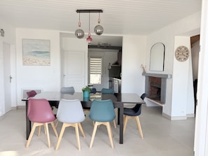 Un comedor con una mesa y sillas, una cocina al fondo y una decoración de pared con temática de playa.