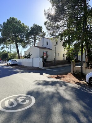 A street with a no entry sign, a white building, and a car parked on the side.