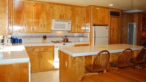 Une cuisine dotée de meubles en bois, d’un four à micro-ondes, d’une cuisinière, d’un réfrigérateur et d’un coin repas avec des chaises.