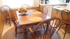 Une table à manger en bois, avec six chaises, un vase de fleurs et deux sets de table.