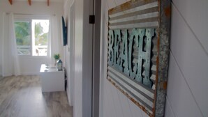 A hallway with a rustic metal sign reading "BEACH" on the wall, a white reception desk, and a wooden floor.