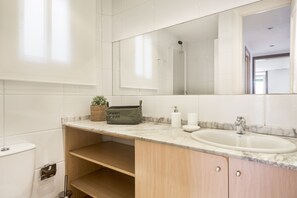 A bathroom with a white sink, a mirror, and a wooden vanity.