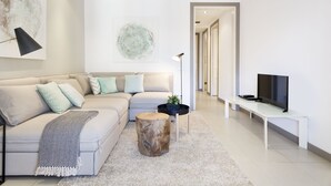 A modern living room with a sectional sofa, a coffee table, and a TV on a stand.
