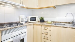 A kitchen with light wood cabinets, a white stove, a microwave, and a sink.