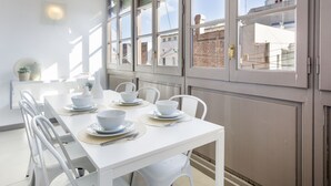 A white dining table set with bowls and cutlery, surrounded by white chairs.