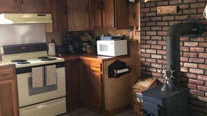 Een keuken met houten kastjes, een fornuis, een magnetron en een bakstenen muur.