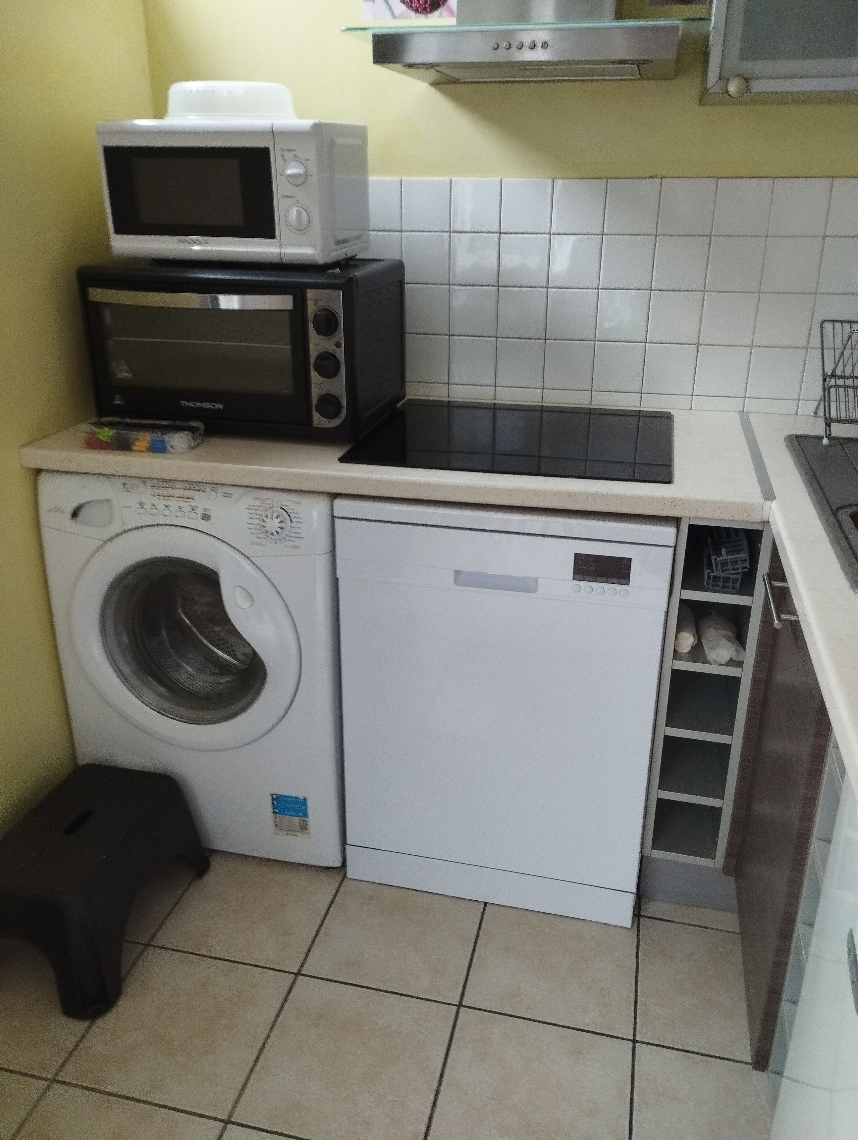 Una cocina compacta con microondas, tostadora y lavadora.