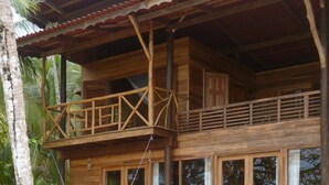 A wooden two-story building with a balcony, large windows, and a hammock. - The Ultimate Beach House (Casa Sol Y La Luna) (Bocas Del Toro)