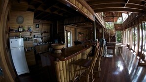 A wooden interior with a bar area, kitchen, and large windows. - The Ultimate Beach House (Casa Sol Y La Luna) (Bocas Del Toro)