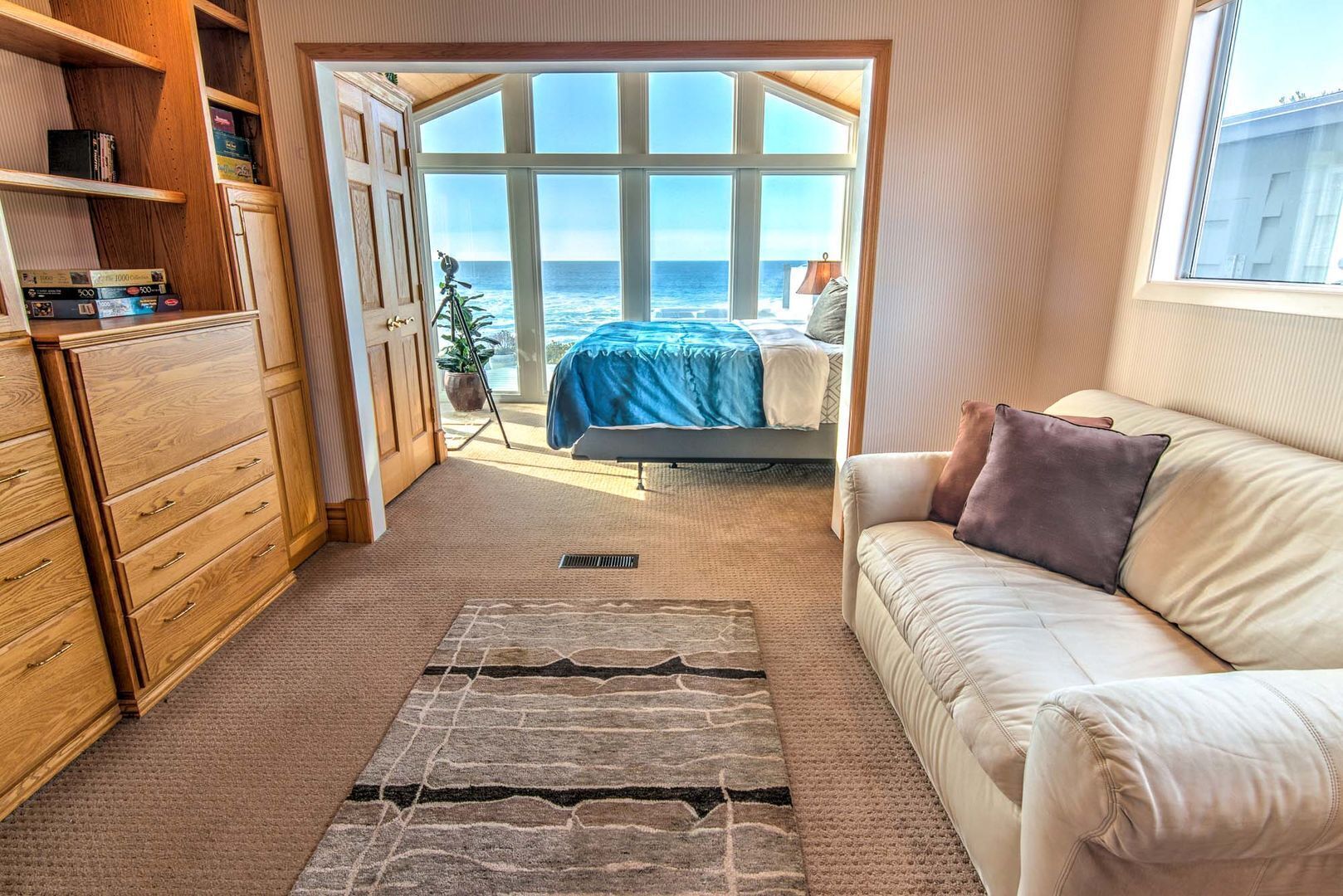 A bedroom with a large window, a bed, a wardrobe, and a sofa.