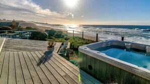 Un patio in legno con idromassaggio e vista sull'oceano.