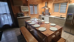 A wooden-paneled kitchen with a central island, stainless steel appliances, and a window with blinds. - CHALET RIVIERA "JACUZZI OFFERT" 3* wifi ANDORRA ax les thermes Orlu ski (Orlu)