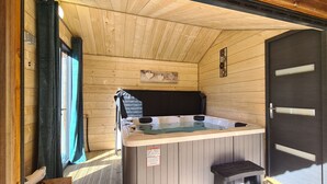 A wooden cabin with a hot tub, a door, and a window with curtains. - CHALET RIVIERA "JACUZZI OFFERT" 3* wifi ANDORRA ax les thermes Orlu ski (Orlu)