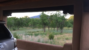 A vehicle parked inside a building with a view of a grassy field and trees. - Peaceful & Roomy - Very close walk (5 Blk) to Historic Plaza dining & shopping (Taos)