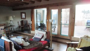 A cozy room with a bed, a chair, and a table. There is a window and a door leading outside. - Peaceful & Roomy - Very close walk (5 Blk) to Historic Plaza dining & shopping (Taos)