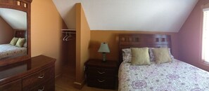 Ein Schlafzimmer mit Bett, Nachttisch, Kommode und Spiegel.