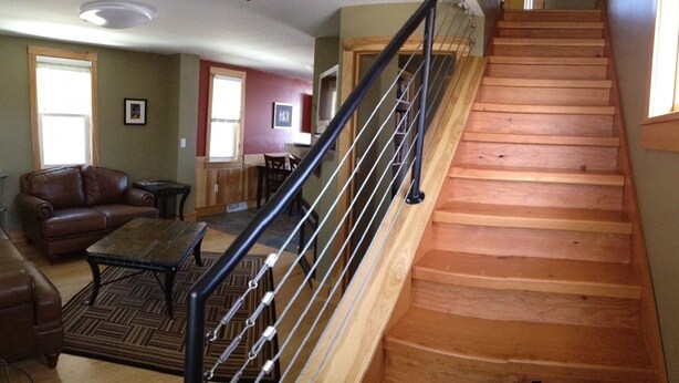 A staircase with wooden steps and a metal handrail leading to a landing. - Minnesota Point Beach House 1-Spectacular Lake Superior View (Duluth)