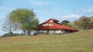 A house with a red-tiled roof, surrounded by a grassy field and trees. - Lupine Ranch - Wine Country Guest House (Templeton)
