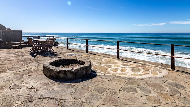 A stone patio with a fire pit and outdoor seating, overlooking the ocean. -  REMODELED OCEANFRONT HOME WITH PRIVATE POOL AND HOT TUB (Playas de Rosarito)
