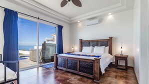 A bedroom with a large bed, a nightstand, a ceiling fan, and a view of the ocean through a sliding glass door. -  REMODELED OCEANFRONT HOME WITH PRIVATE POOL AND HOT TUB (Playas de Rosarito)
