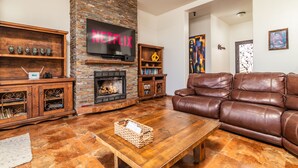 A living room with a fireplace, leather sofa, wooden entertainment unit, and a flat-screen TV displaying 'NETFLIX'. -  REMODELED OCEANFRONT HOME WITH PRIVATE POOL AND HOT TUB (Playas de Rosarito)