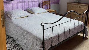 A bedroom with a sloped ceiling, a skylight, a bed with a metal frame, a wooden chair, a dresser, and patterned rugs. - Apartment in a quiet village (Briançon)