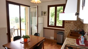 A compact kitchen with a dining table, chairs, a gas stove, a sink, and a window overlooking a balcony. - Separate gite without immediate neighbour on laid out field, a lot of space... (Les Granges-Gontardes)