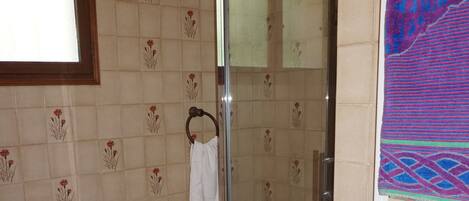 Ein Badezimmer mit einer gläsernen Dusche, einer Badewanne und einem weißen Handtuchhalter.