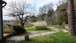 A stone pathway leading through a garden with a tree, grass, and a wooden bench. - Separate gite without immediate neighbour on laid out field, a lot of space... (Les Granges-Gontardes)