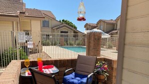 A patio area with a pool, a table with chairs, and a hanging light fixture. - Your Perfect Getaway Awaits- Ideal for Students and Families (Chandler)