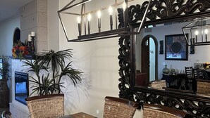 A dining area with a wooden table, wicker chairs, and a modern chandelier. - Gorgeous Ocean View- completely remodeled 2/2, Great Decor, Fireplace, King Beds (Puerto Penasco)