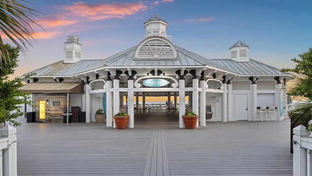 Um hotel com entrada coberta, uma placa central e um deck de madeira que leva à entrada.