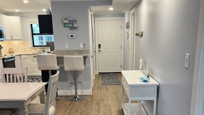 A modern kitchen with white cabinets, a dining table with chairs, and a small island with a sink. - Crescent Beach Escape – 2BR Beachfront Condo on Siesta Key
Steps to the sand! (Siesta Key)