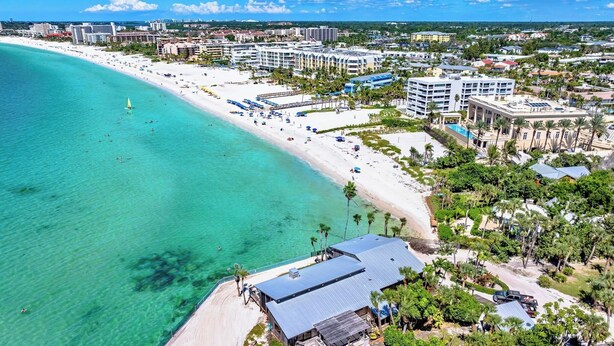 An aerial view of a coastal resort with a sandy beach, clear turquoise waters, and a mix of residential and hotel buildings. - Crescent Beach Escape – 2BR Beachfront Condo on Siesta Key
Steps to the sand! (Siesta Key)