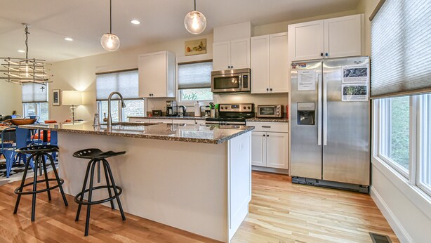 A modern kitchen with white cabinets, stainless steel appliances, and a large island with stools.