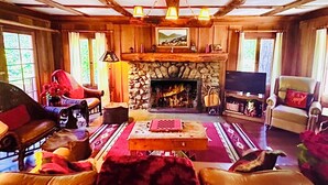 A cozy living room with a stone fireplace, wooden beams, leather sofas, and a television. - 5 STAR **STRAWBERRY CORNER** CLASSIC CABIN ON CREEK, 1 MINUTE WALK TO VILLAGE! (Idyllwild)