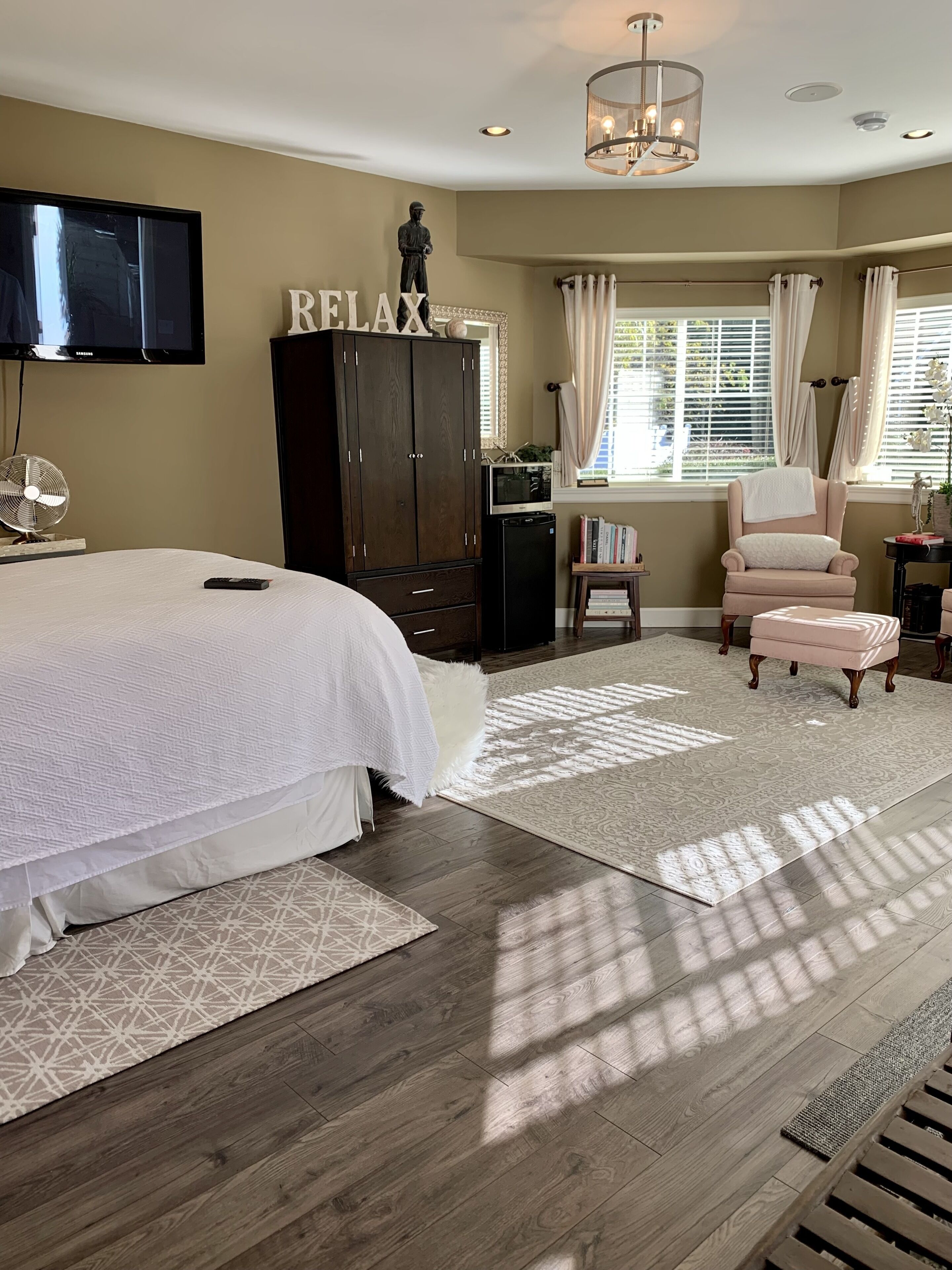 A bedroom with a large bed, a wardrobe, a desk, a chair, and a television.