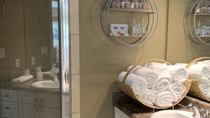 Une salle de bain avec une douche en verre, des meubles blancs et un meuble-lavabo avec un miroir.
