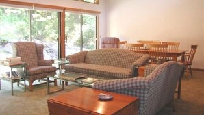 A living room with a sofa, armchair, coffee table, and dining table.