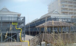 Ein Strandhotel mit Sandstrand, einer Holzkonstruktion und einer Treppe zum Strand.