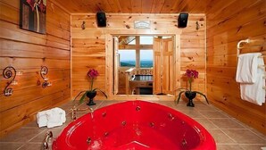 En træhytte med et stort rødt jacuzzi, trævægge og udsigt til bjergene.