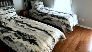 Un dormitorio con dos camas, cabeceros de madera, una ventana y piso de madera.