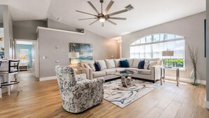 A modern living room with a sofa, armchair, coffee table, and a ceiling fan. - True Happiness In Paradise!  Close To Everything!  Heated Pool! (Marco Island)