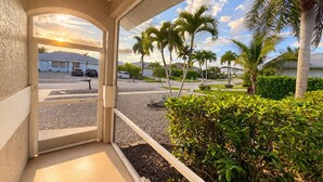 A view from a balcony with a clear sky, palm trees, and a street with parked cars. - True Happiness In Paradise!  Close To Everything!  Heated Pool! (Marco Island)