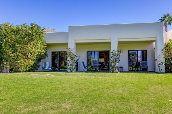 A modern two-story house with a flat roof, large windows, and a well-maintained lawn.